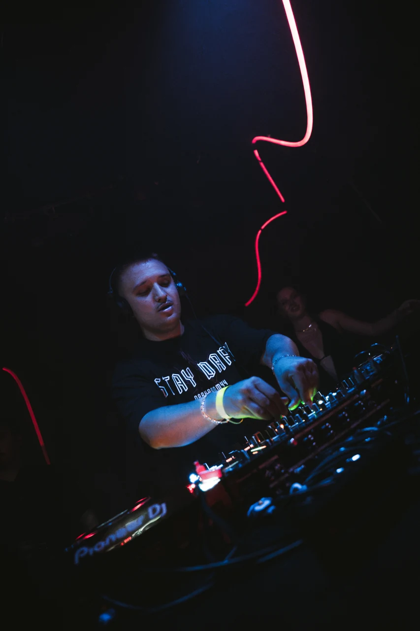DJ am Mischpult bei 0711 Raves mit blauem Licht und roten Lichtspuren