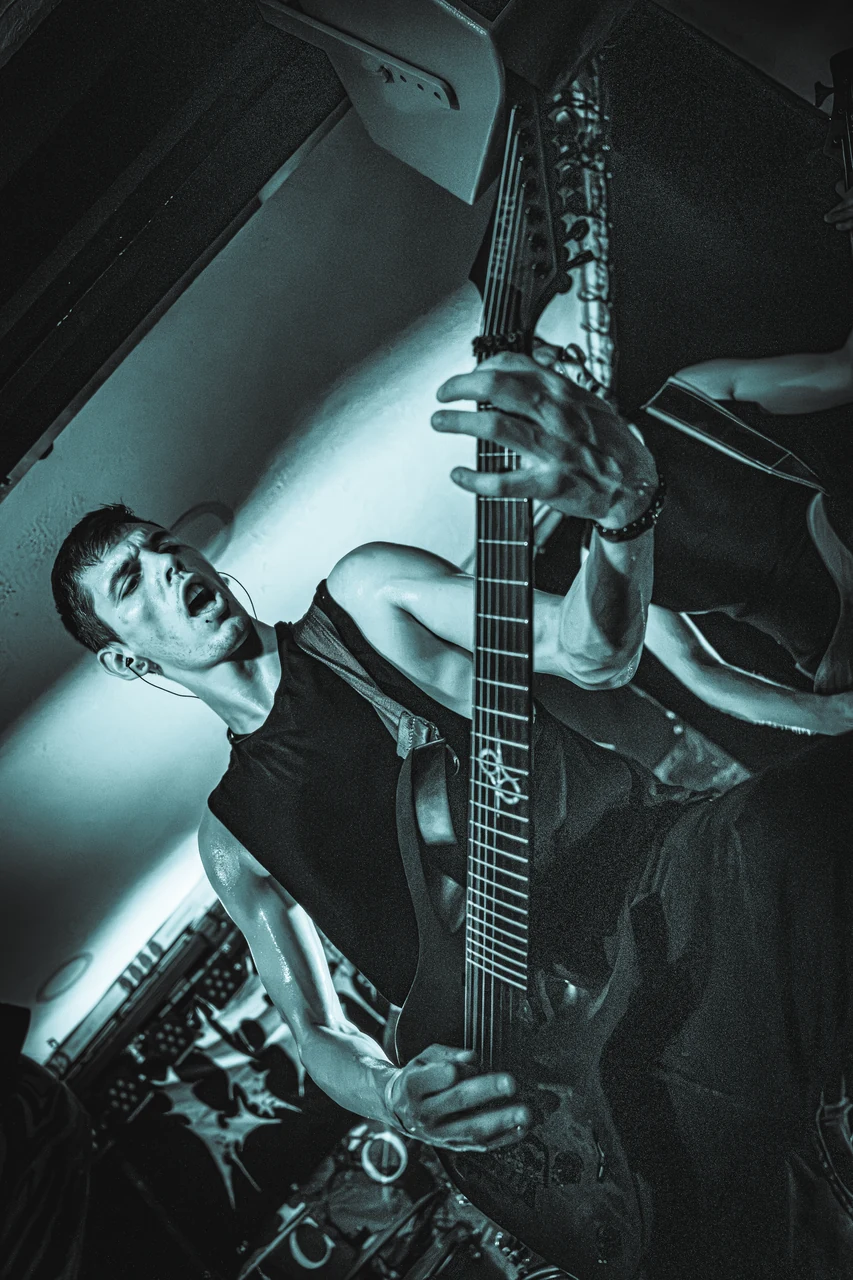 Litarum-Bassist beim Spielen unter türkisfarbenem Bühnenlicht